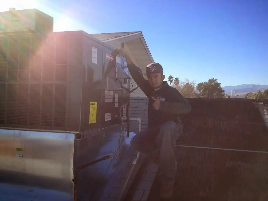 HVAC technician performing Heat Pump Repair on a rooftop unit in Mustang